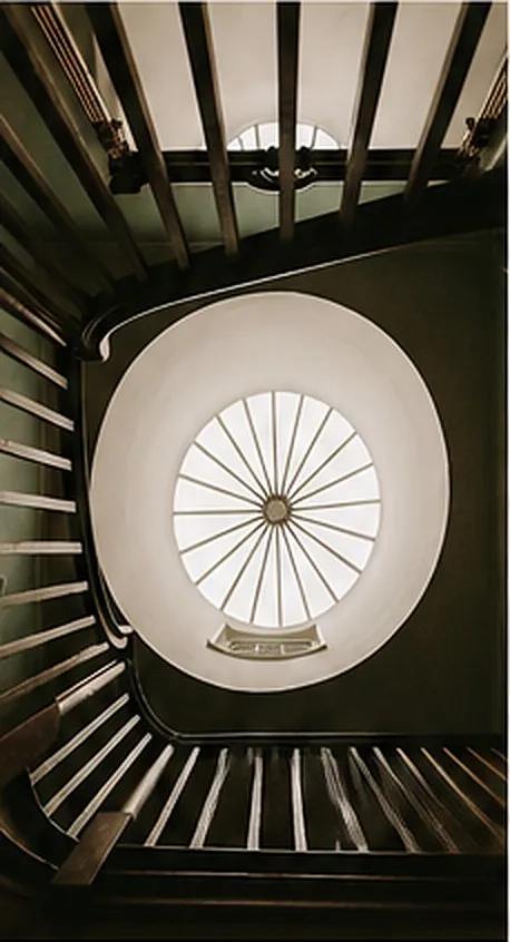 A cantilevered staircase spiralling beneath a round roof lantern.